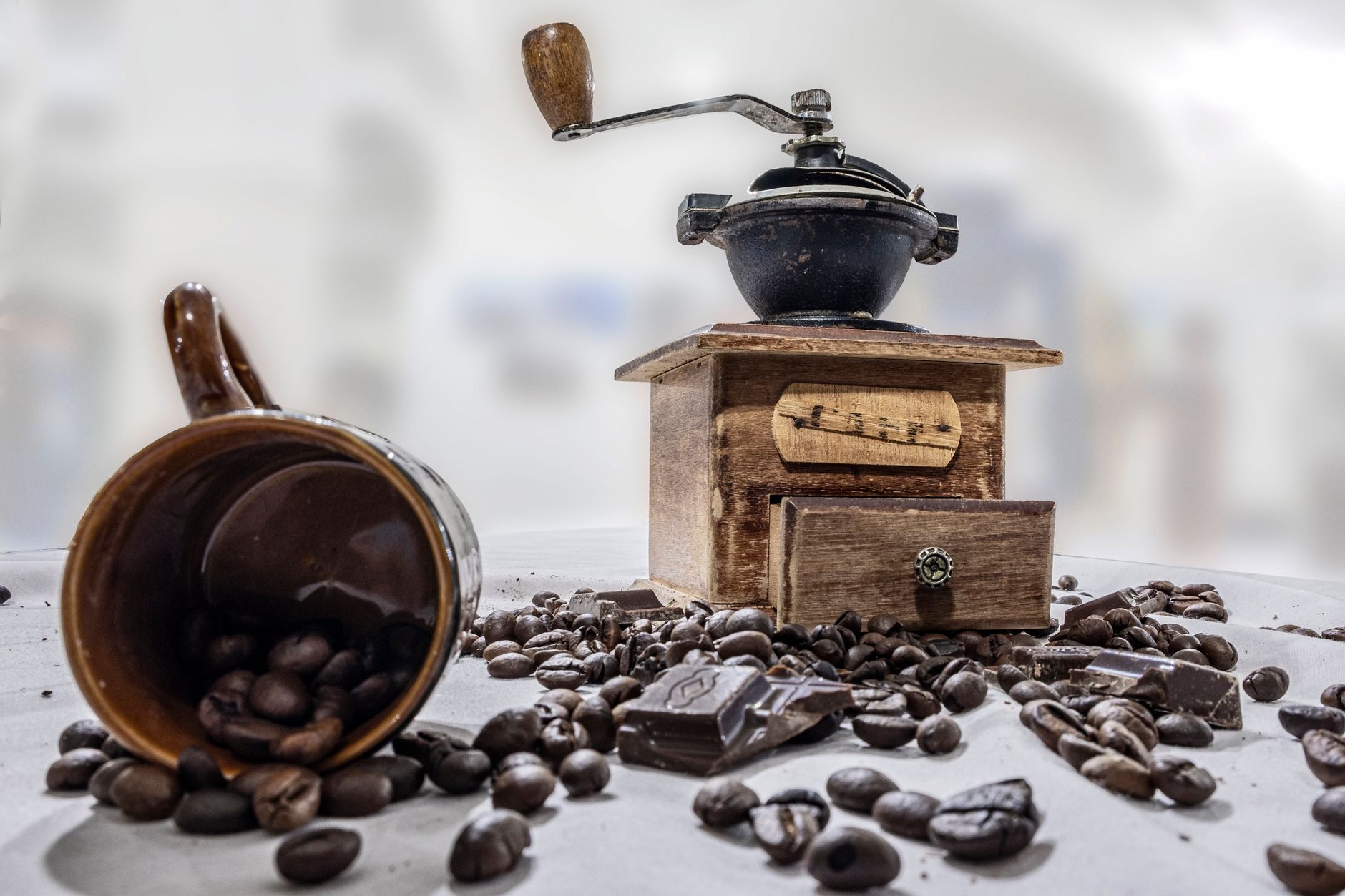 A burr coffee grinder next to a pile of freshly ground dark-roast coffee