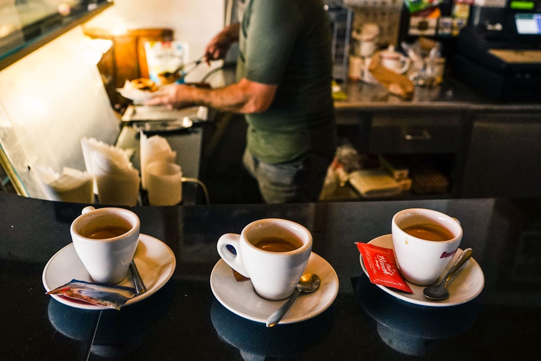 The counter of a historic Neapolitan bar with a chalkboard tracking paid suspended coffees