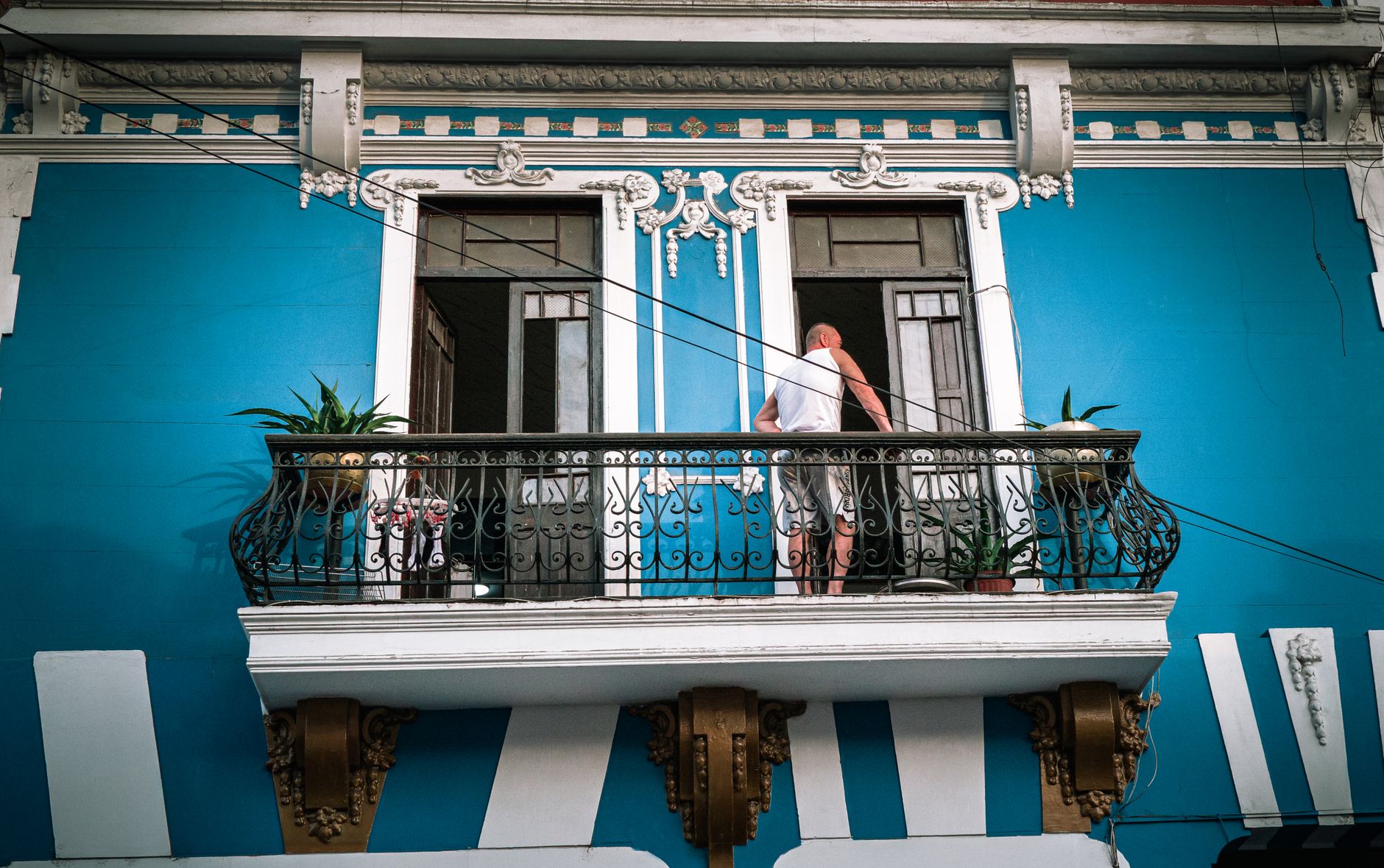 A vintage theater-style illustration of a man preparing coffee on a balcony