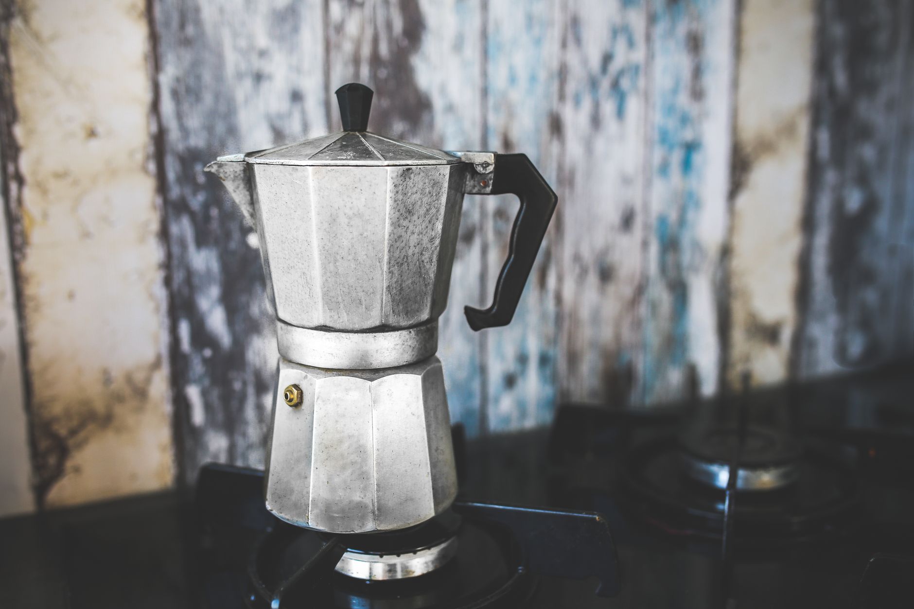 A classic aluminum moka pot brewing on a gas stovetop