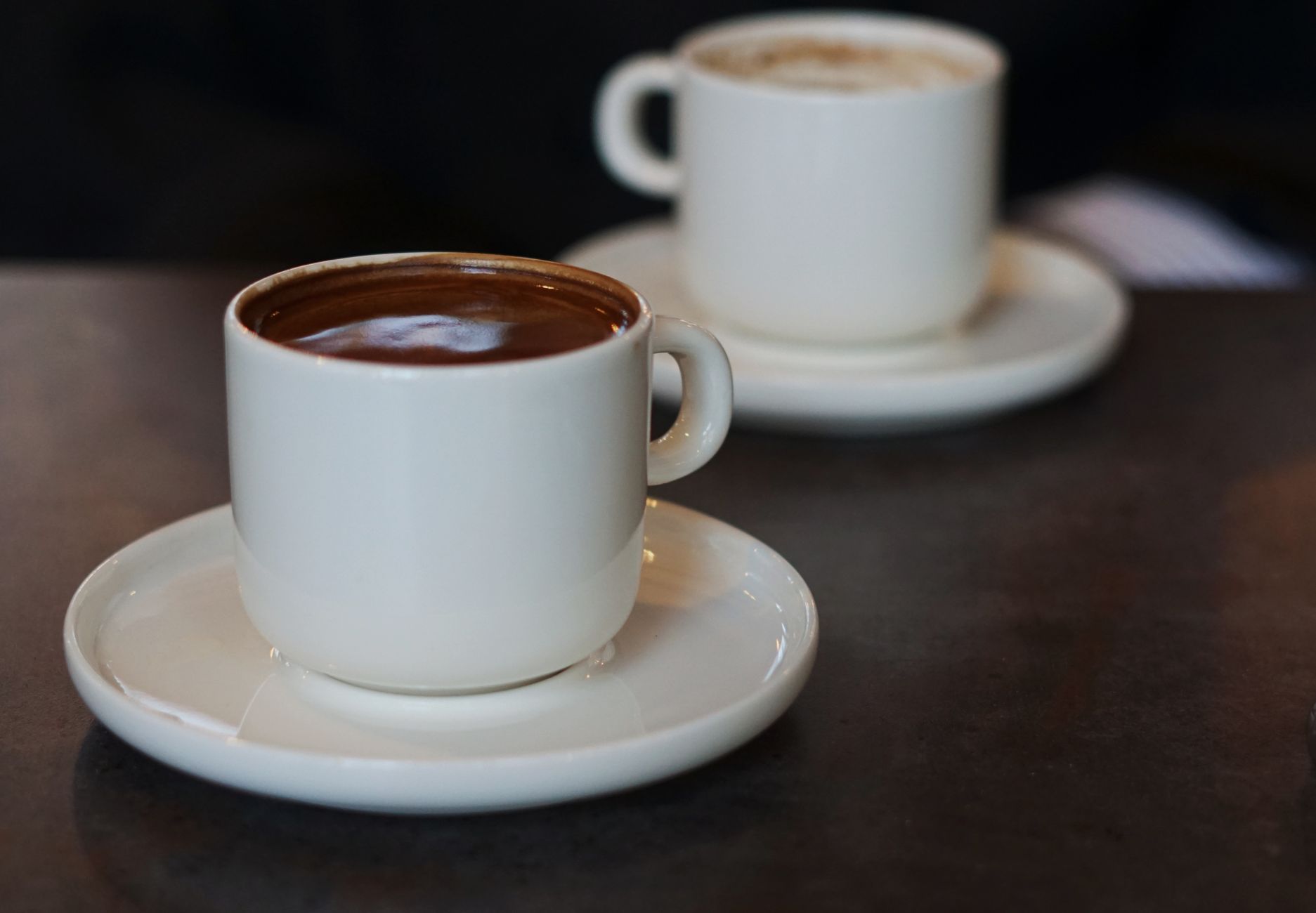 Two espresso cups side by side, one dark and dense, one lighter and more acidic